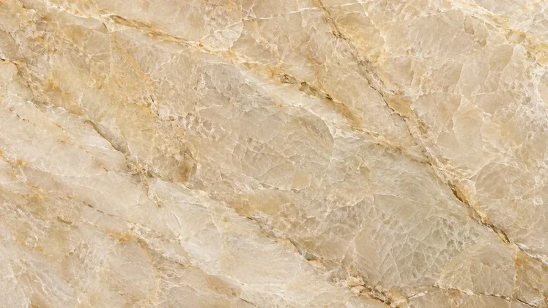 Detalle de cuarcita natural pulida en tonos beige y dorados con vetas y brillo mineral