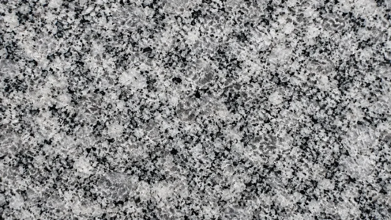 Detalle de superficie de granito gris pulido con grano cristalino blanco, negro y gris